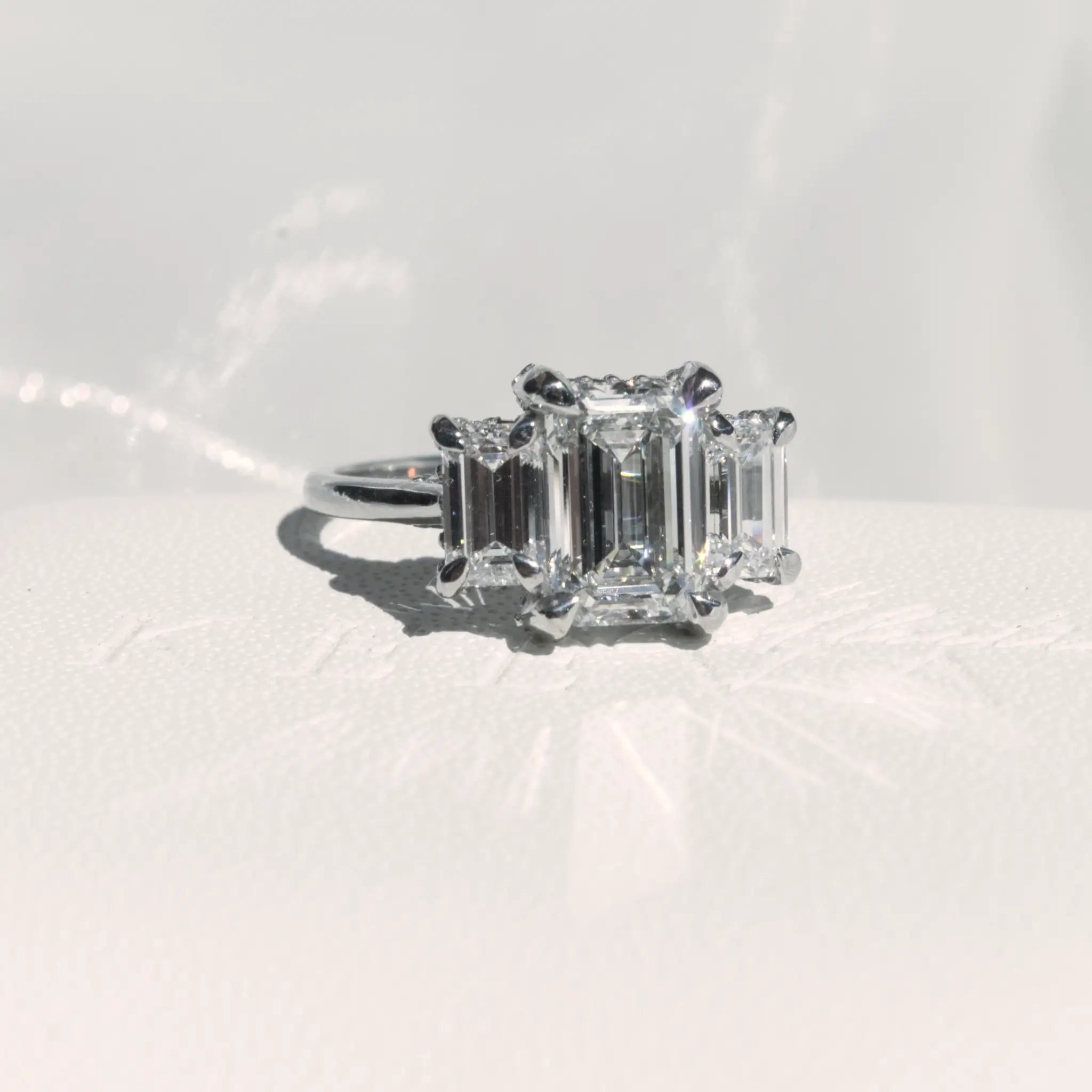 Trilogy Emerald cut Diamond Engagement Ring with infinity hidden halo.