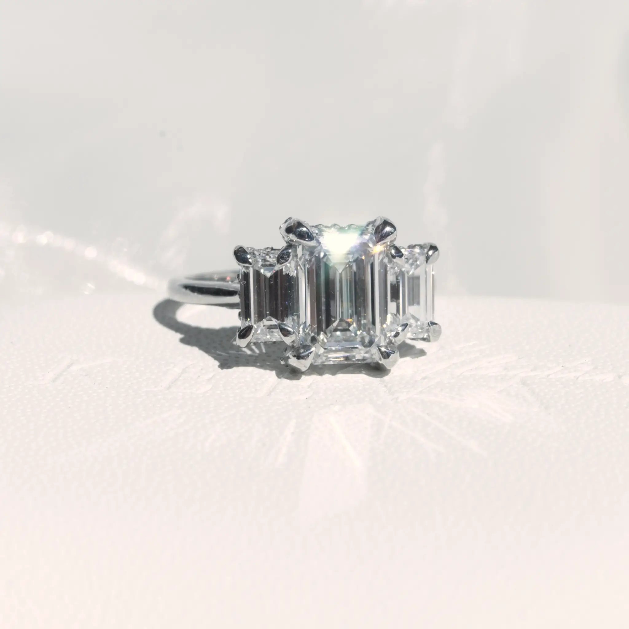 Trilogy Emerald cut Diamond Engagement Ring with infinity hidden halo.