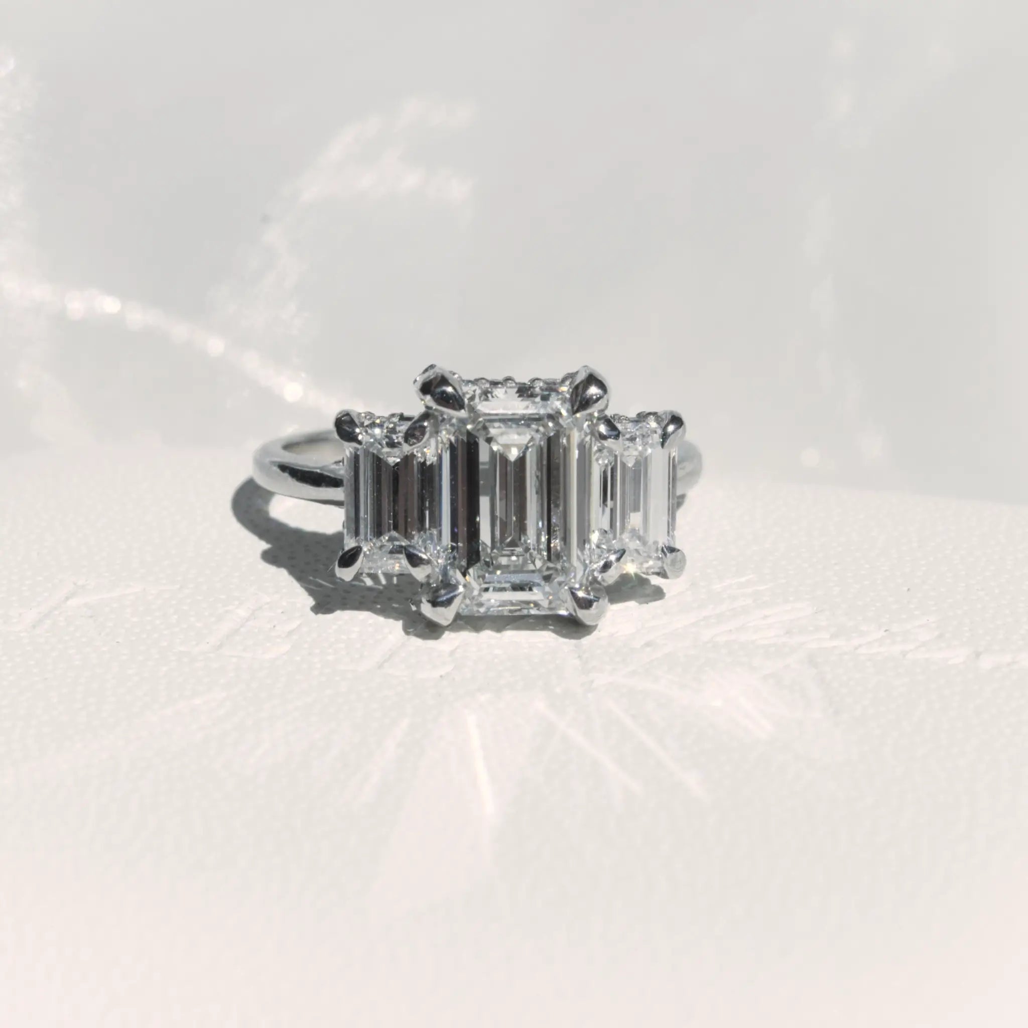 Trilogy Emerald cut Diamond Engagement Ring with infinity hidden halo.