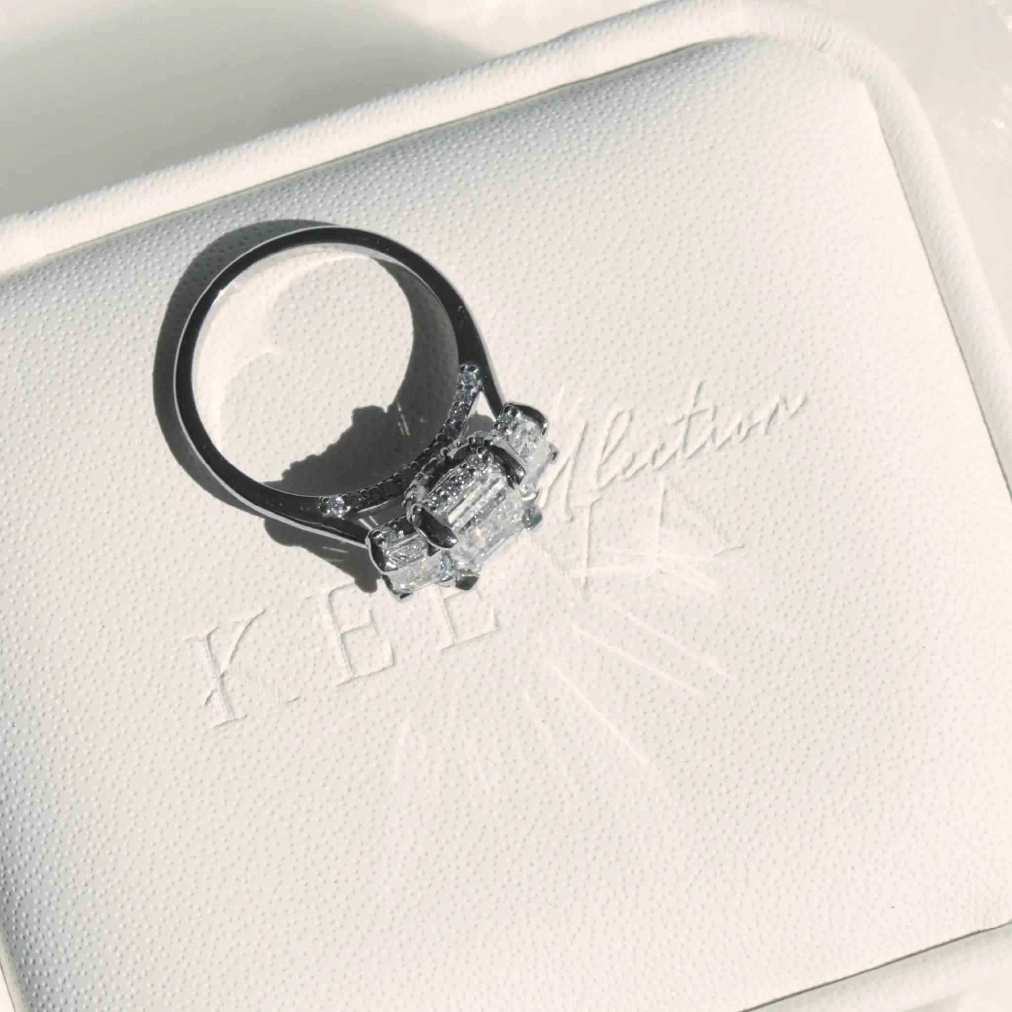 Trilogy Emerald cut Diamond Engagement Ring with infinity hidden halo.