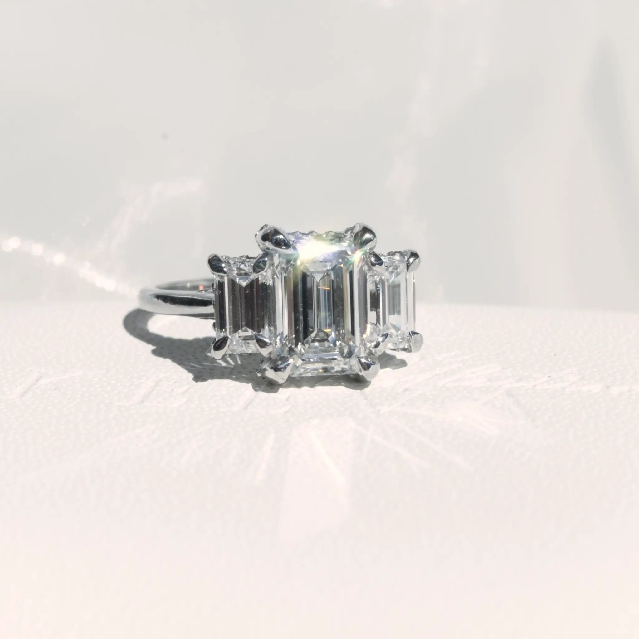 Trilogy Emerald cut Diamond Engagement Ring with infinity hidden halo.